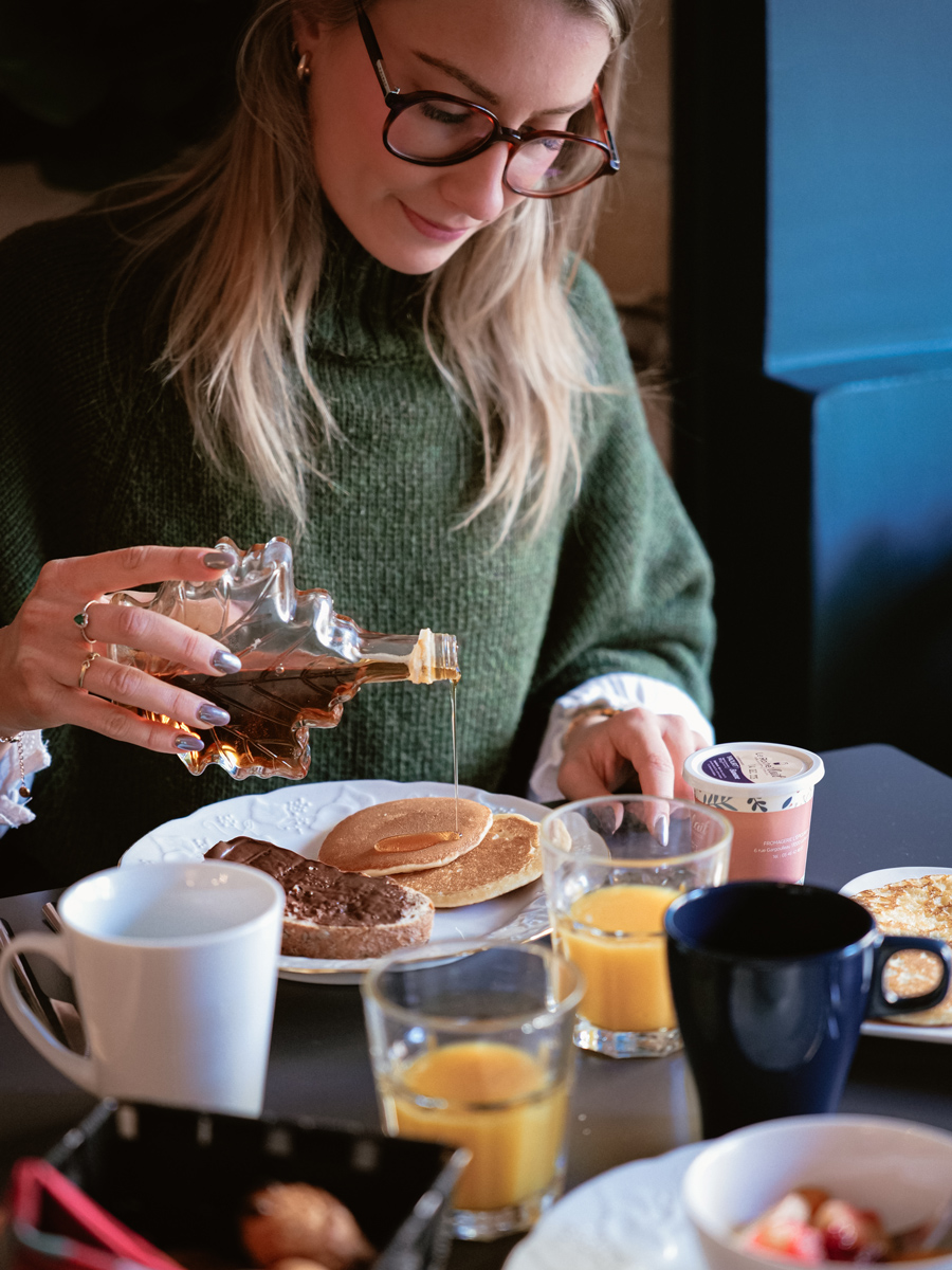 Cliente qui verse du sirop d'érable sur ses pancakes au petit déjeuner de l'hôtel de La Paix à La Rochelle